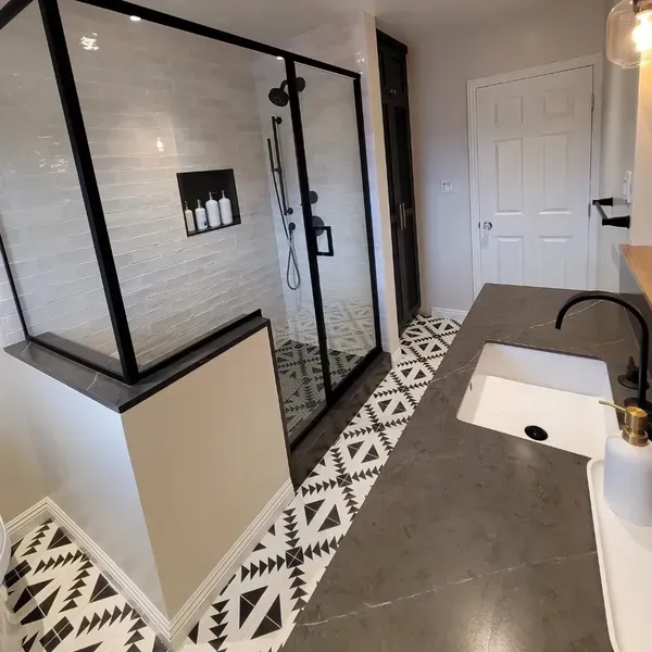 Bend OR bathroom remodel featuring curbless walk-in shower with black-frame glass enclosure, white subway tile, and black-and-white patterned floor tile